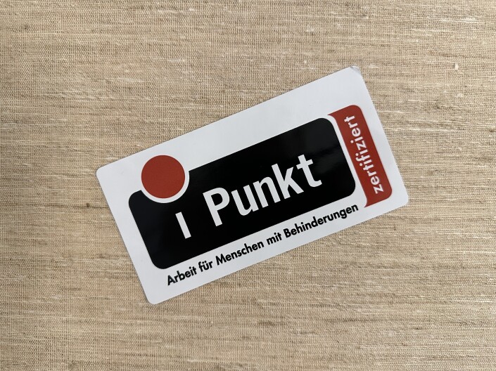 Aufkleber mit dem iPunkt Logo auf einem neutralen Hintergrund.